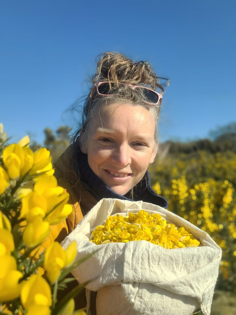 Rachel Lambert stands outdoors with gorse flowers gathered to make sweet treats