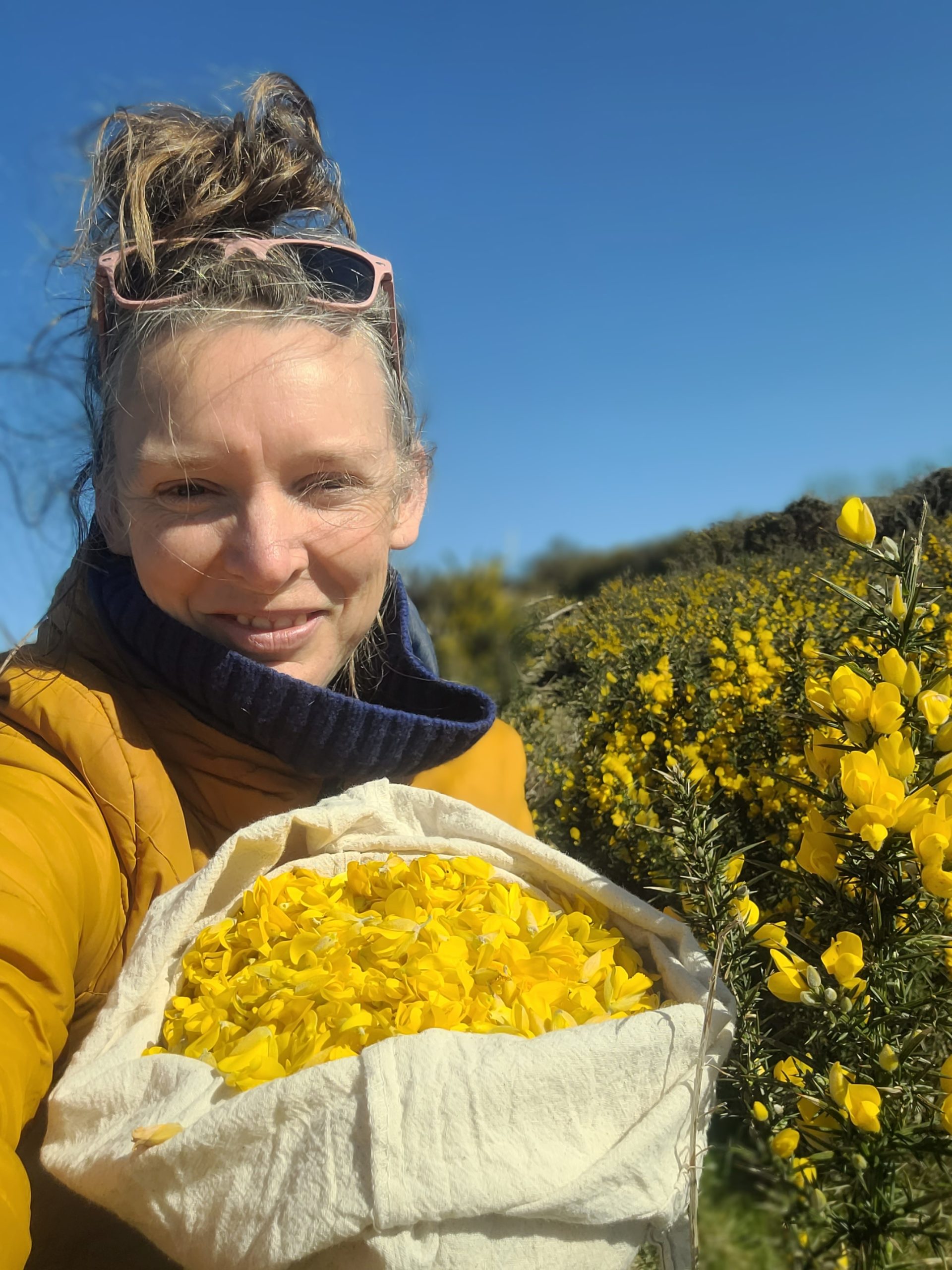 Rachel Lambert stands outdoors with gorse flowers gathered to make sweet treats