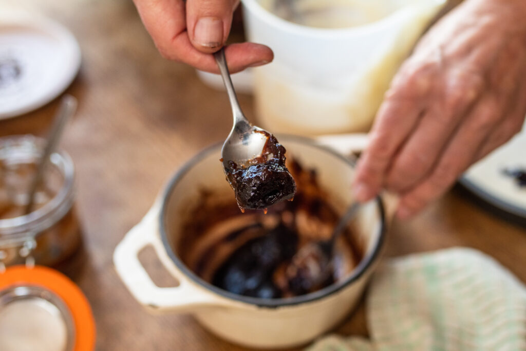 A small saucepan of haw berry and star anise jam with a spoon