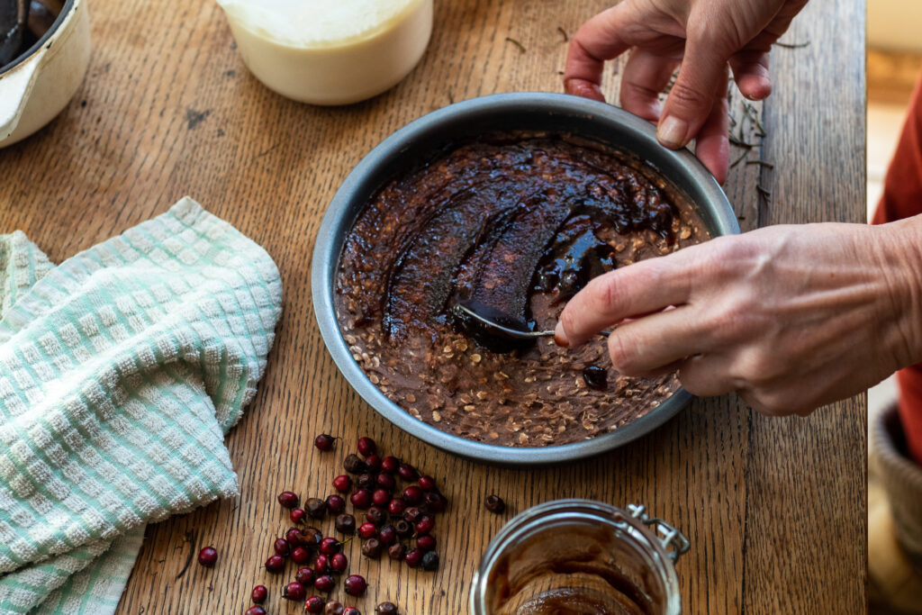 Aerial view of spreading a layer of haw berry jam on the chocolate base of a baked cheesecake