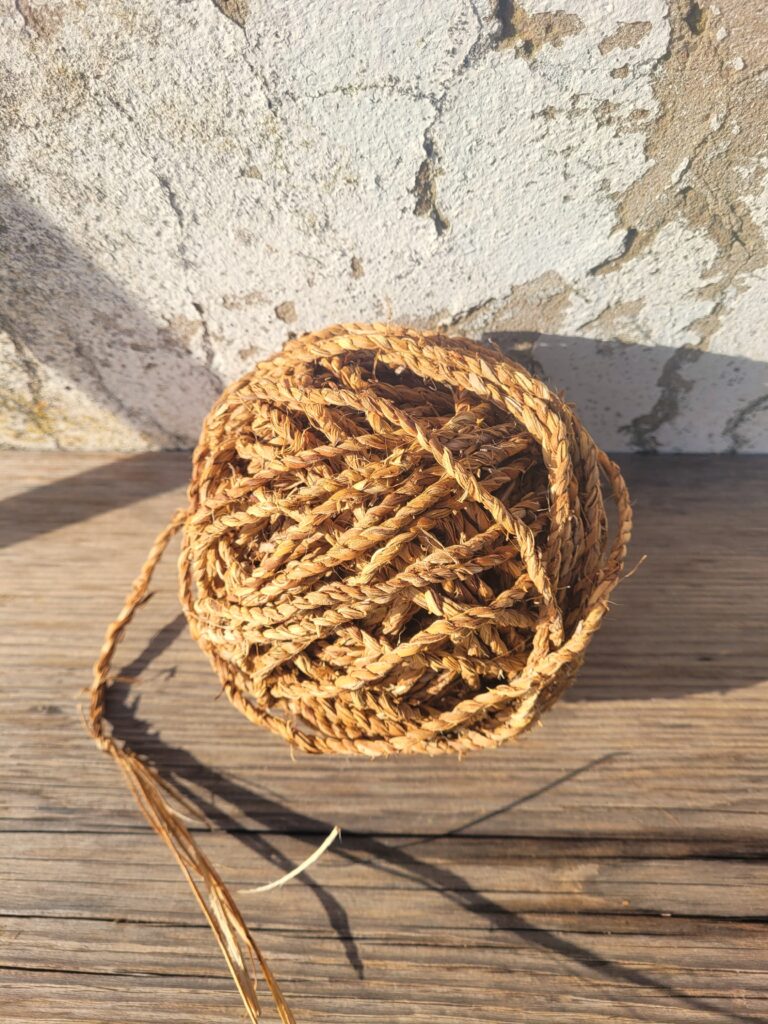 Large ball of string (cordage) on a wooden bench with a rustic white background