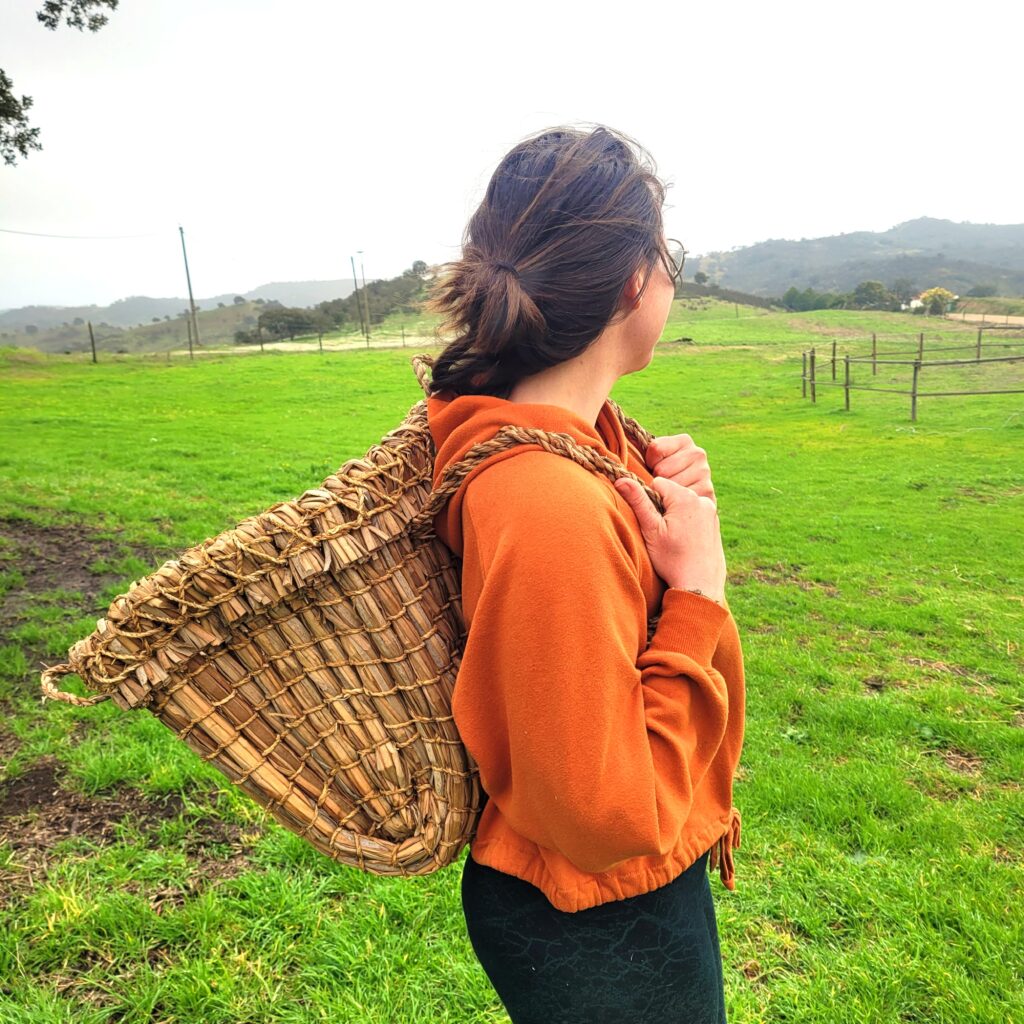 Woman standing side on and looking to the left with a kishie style rucksack on her back 