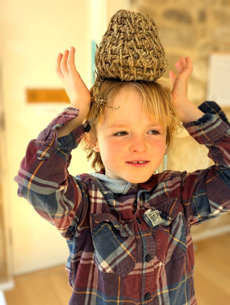 Young boy with a coiled pot made from daffodils on his head!