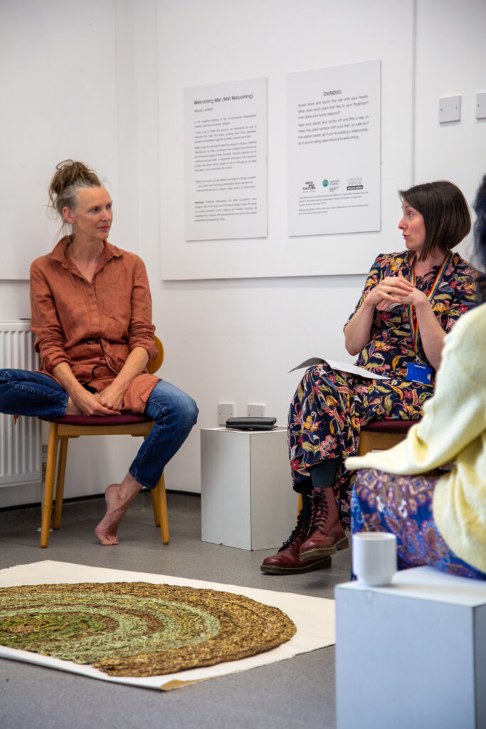Artist and Craftsperson Rachel Lambert sitting in front of the Welcoming Mat and being interviewed