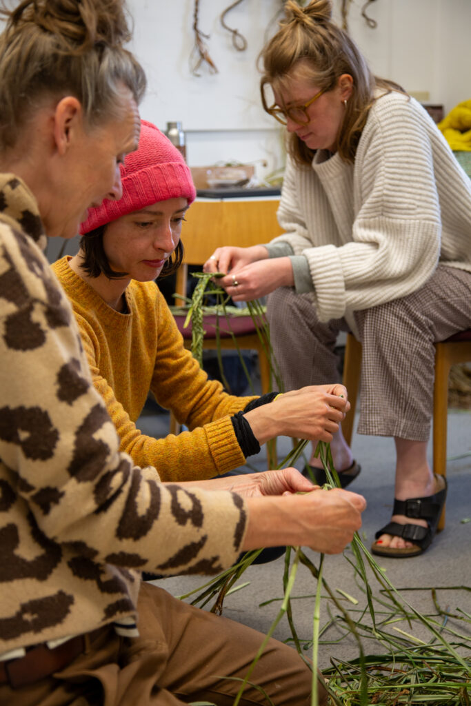Rachel Lambert tutoring adults on weaving with plants
